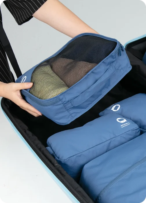 Person packt Kleidung mit blauem Organizer-Set – Link zur Kategorie Reisezubehör