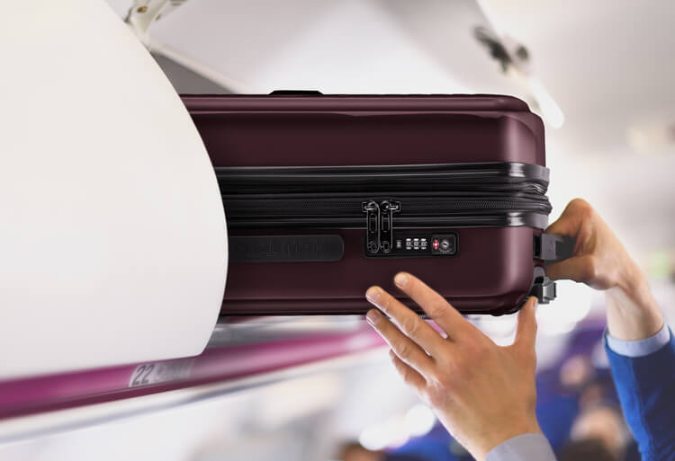Ein Handgepäckkoffer von Hauptstadtkoffer wird in der Gepäckablage im Flugzeug verstaut